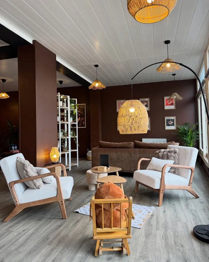 Le salon : fauteuils clairs, suspensions en osier et plantes, baies vitrées
