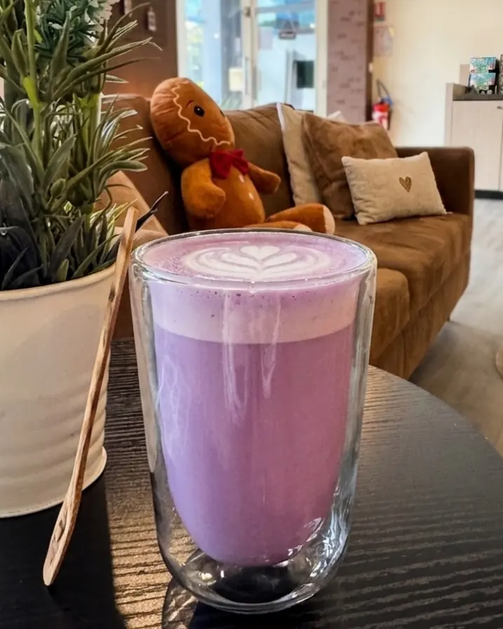 Ubé latte chaud violet dans une tasse en verre, posé sur une table du salon